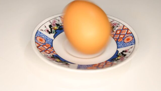 A man spins a boiled egg to see if it is boiled.