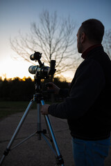 Amateur astronomer observing Sun eclipse and Sun with a telescope and special solar filter.