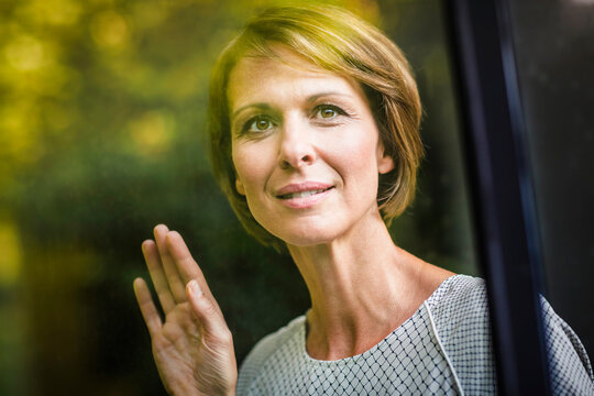 &nbsp;Frau nachdenklich am Fenster Blick nach draussen, Spiegelungen Laubbaum, Bayern, Deutschland