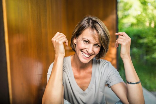 gl&uuml;ckliche Frau in der Sonne vor ihrer neuen Immobilie, Bayern, Deutschland