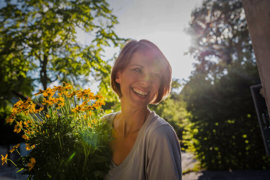 gl&uuml;ckliche Frau mit Blumentopf vor einer neuen Immobilie, Bayern, Deutschland