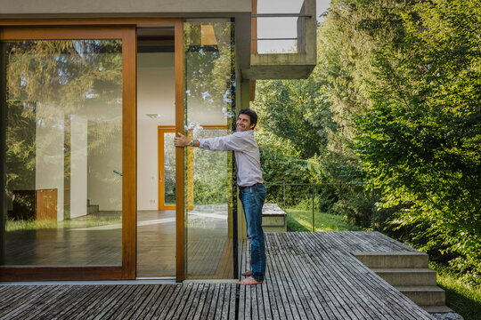 gl&uuml;cklicher Mann auf der Terrasse umarmt  neu gebautes Haus, Bayern, Deutschland