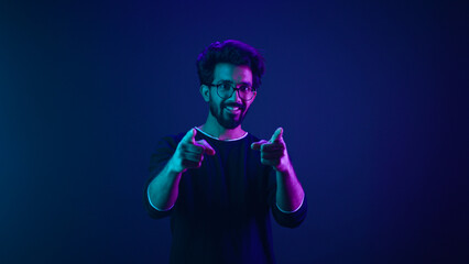 Portrait in neon ultraviolet happy Indian guy Arabian man worker coder hacker computer engineer...