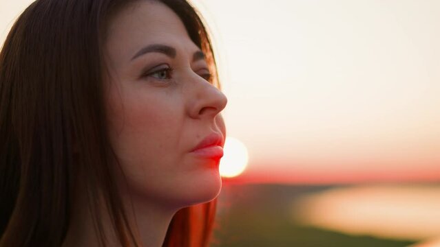 Woman with negative thoughts against dusk sun closeup. Beautiful lady deals with hard feelings walking at evening countryside. Melancholic mood
