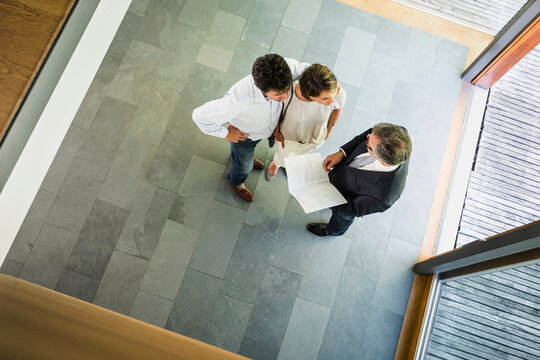 Paar mit Immobilienmakler schauen Vertragsunterlagen an einer neuen Immobilie, Vogelperspektive, Bayern, Deutschland