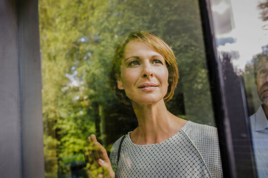 &nbsp;Frau nachdenklich am Fenster Blick nach draussen, Spiegelungen Laubbaum, Bayern, Deutschland