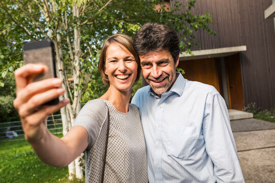 gl&uuml;ckliches Paar macht Selfie vor einer neuen Immobilie, Bayern, Deutschland