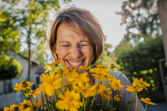 glückliches Frau mit Blumenstrauss vor einer neuen Immobilie, Bayern, Deutschland