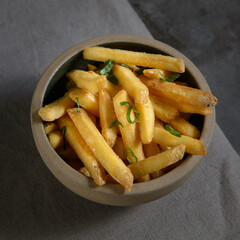 French fries in a bowl, fried potatoes. Black background. Top view.