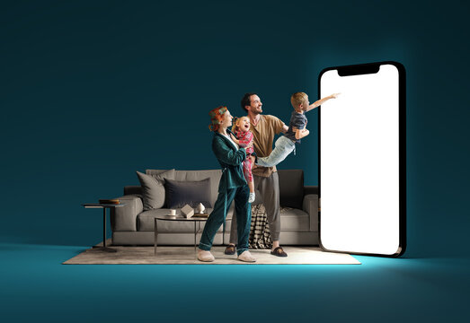 Family interacting with huge 3D model of smartphone in living room against blue background. Online shopping, delivery services, sales. Modern technologies. Mockup for ad, text, design, logo