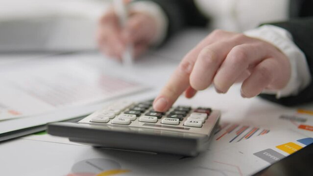 A girl economist keeps track of expenses and profits, using a calculator and a computer to manage finances. A financial manager reviews reports and documents on a desktop, planning a budget, and