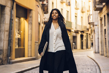 young woman walking through the city using a device 