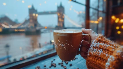 Poster de jardin Tower Bridge Close-up of a female hand holding a cup of coffee and Tower Bridge  is in the background, first-person photo, blurred background, travel image with well known destination
