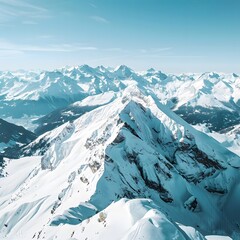 Aerial drone capture of the serene, snow-capped Alpine peaks under a clear, blue sky showcasing a panoramic winter wonderland.