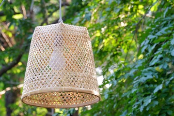The Oriental style of wooden lamp hanging on a black rope top view with big trees and green nature background 