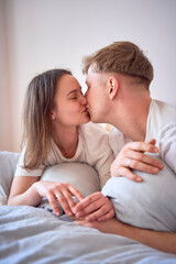 a young beautiful couple hugging and kissing in bed, wellness at home
