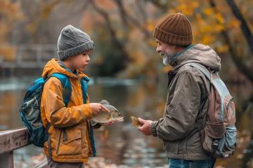 Photo sur Plexiglas Descente vers la plage Happy son holding caught fish while standing on boardwalk with father at riverbank