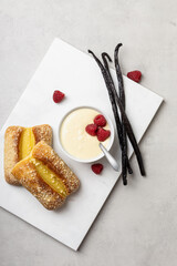 Vanilla pudding with raspberries in white bowl.