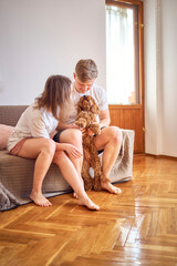a young couple hugs their dog in the living room
