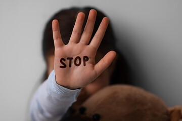 No child abuse. Little girl showing hand with written Stop on palm, selective focus