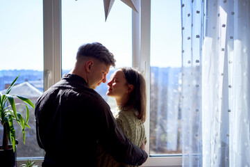 beautiful young couple kissing in the backlight against the window
