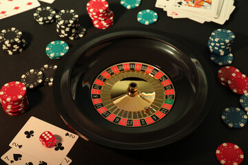 Roulette wheel, playing cards and chips on table, closeup. Casino game