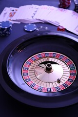 Roulette wheel, playing cards and chips on table, closeup. Casino game