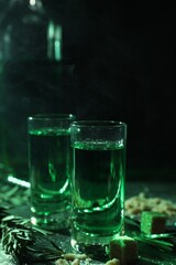 Absinthe in shot glasses, rosemary and brown sugar on table, closeup. Alcoholic drink
