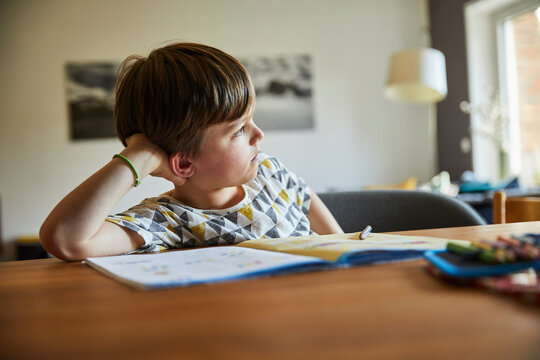 Kind tr&auml;umt beim Hausaufgaben machen aus dem Fenster, M&uuml;nchen, Bayern, Deutschland