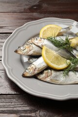 Fresh raw sprats, dill and cut lemon on wooden table