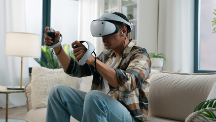 African American man player enjoying at home couch playing vr game fight boxing ethnic guy gamer male play online fighting wear headphones virtual reality 3d helmet glasses hold controllers joysticks - obrazy, fototapety, plakaty