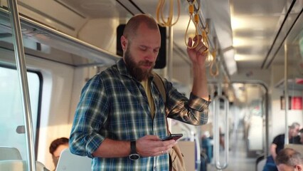 Young adult playing video games or watching social media content while heading to work office in public transport, subway, suburb commuter train. Technology in daily life addiction to digital gadget