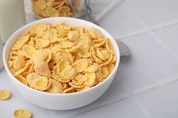 Breakfast cereal. Tasty crispy corn flakes in bowl on white tiled table, closeup. Space for text