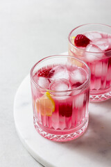 Raspberry cocktail with ice in a glass on a light background
