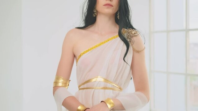 Fantasy portrait woman queen warrior holding ancient steel sword in hand. silk clothing white stylish dress gold crown vintage costume. Long black hair fashion model beauty face blue eyes sexy lips