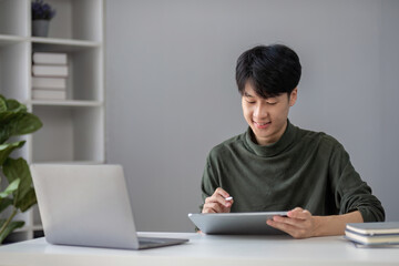 Fototapeta premium Portrait of a handsome young office worker intently studying how to do a presentation project on a laptop in his office.