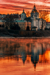 Fototapeta na wymiar Mirror reflection in the water of the Epiphany Cathedral and the dawn red sky. City of Polotsk, Western Dvina River, Belarus.