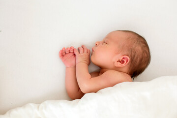 Cute baby boy, peacefully sleeping in bed, covered with white blanket