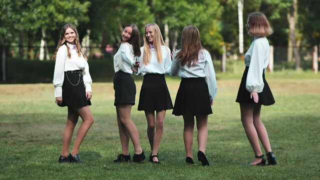 Funny schoolgirls posing and goofing around in a meadow.