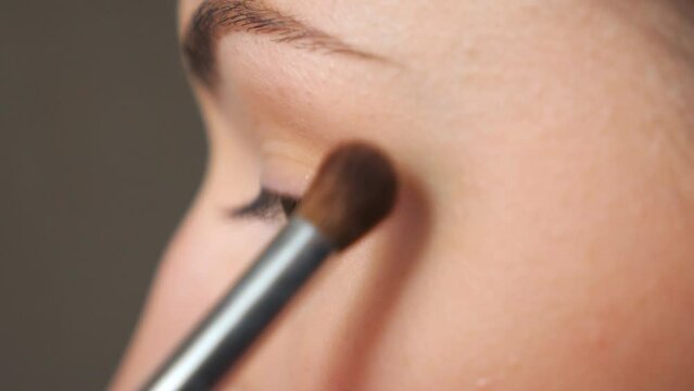 Young woman applying cosmetic on eyebrows. Pretty girl taking care of herself doing makeup with brush. Attractive model in beauty salon. Concept of fashion and style. Detail view Close up