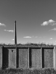 An ancient factory chimney and concrete fence in today's landscape