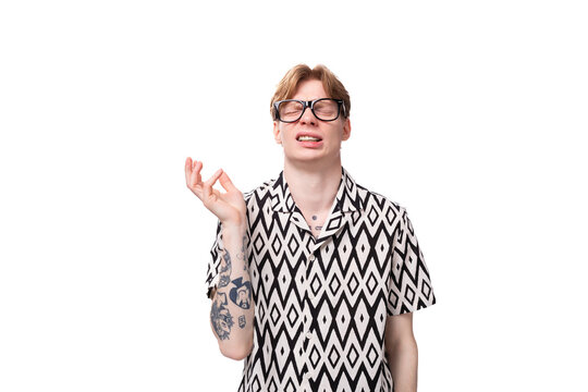 a young man with golden hair and a tattoo on his arms wears glasses for image and a black and white shirt