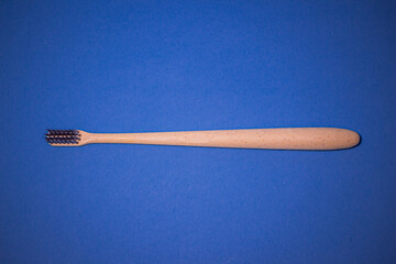 Environmentally friendly natural wooden toothbrush on blue background. Health care, copy space