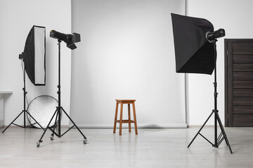 Empty stool surrounded by professional lighting equipment in photo studio