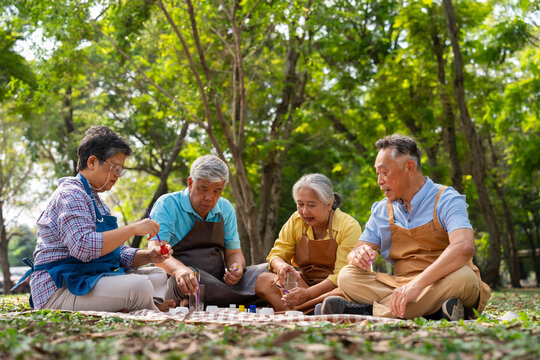 A group of Asian senior people enjoy painting cactus pots and recreational activity or therapy outdoors together  at an elderly healthcare center, Lifestyle concepts about seniority