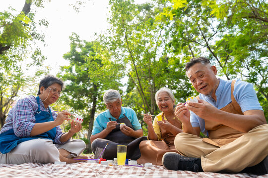 A group of Asian senior people enjoy painting cactus pots and recreational activity or therapy outdoors together  at an elderly healthcare center, Lifestyle concepts about seniority