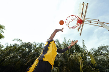Player throwing ball in basket when playing outdoors, view from below