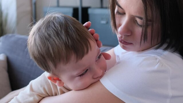 Caring Caucasian mother strokes crying son head, comforting and embracing his. Showing maternity love and care. Helping to cope with stress.
