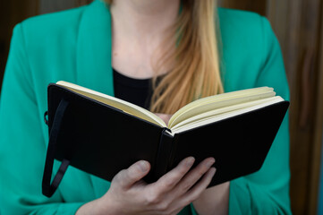 Elegenacka studentka trzyma w dłoniach otwarta książkę i czyta