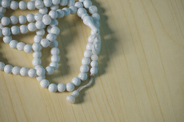 Prayer beads white for Ramadan, isolated on a wood background